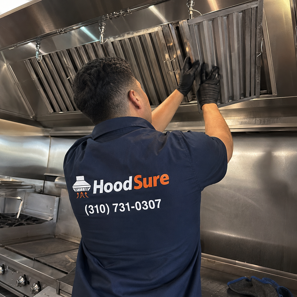 HoodSure technician reinstalling hood filters in a commercial kitchen